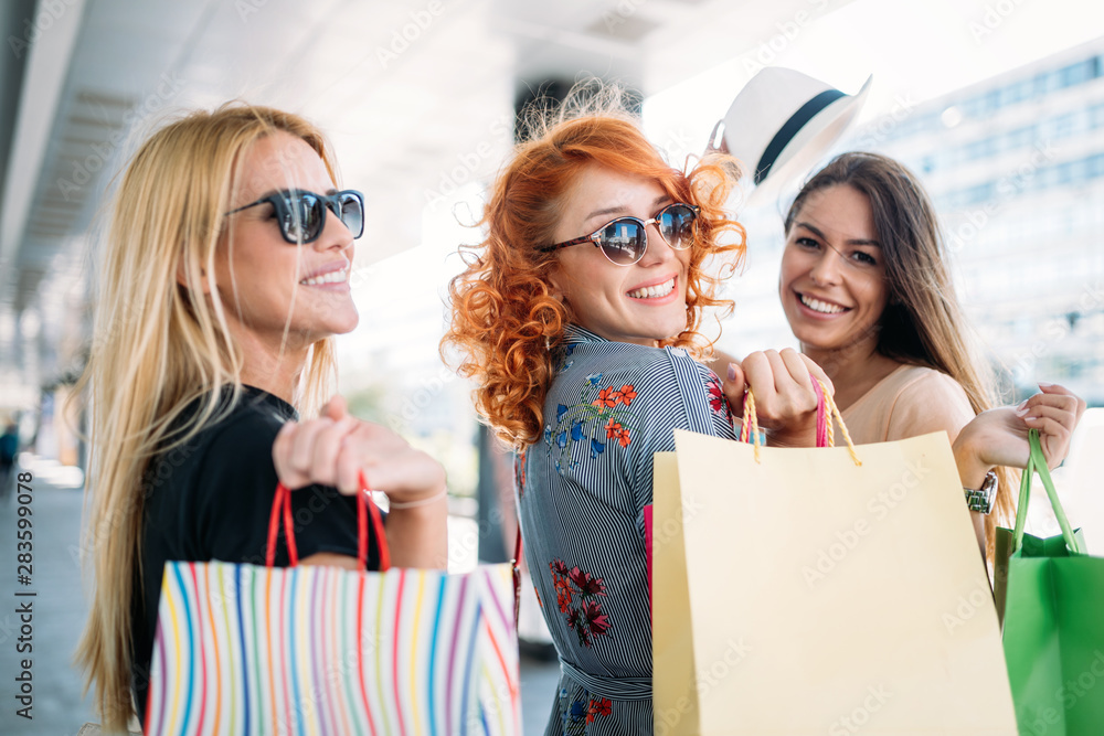 Beautiful happy girls holding shopping bags and smiling outdoors Beautiful happy girls holding shopping bags and smiling outdoors