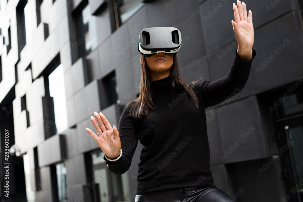 Female Using Virtual Reality Glasses And Wearing Black In Futuristic City Female Using Virtual Reality Glasses And Wearing Black In Futuristic City