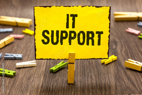 Text sign showing It Support. Conceptual photo Lending help about information technologies and relative issues Clothespin holding yellow paper note several clothespins wooden floor photo