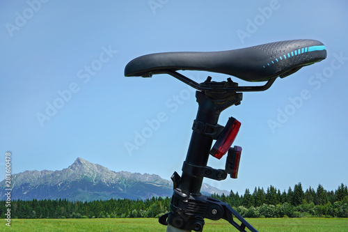 Detail on bike saddle, with green meadow and mountains mount Krivan in background - cycling in country concept