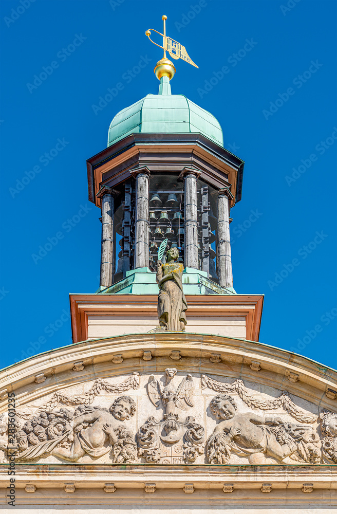 Bell tower and  steeple with golden symbols as flag at the top in downtown of Magdeburg, Germany, closeup, details