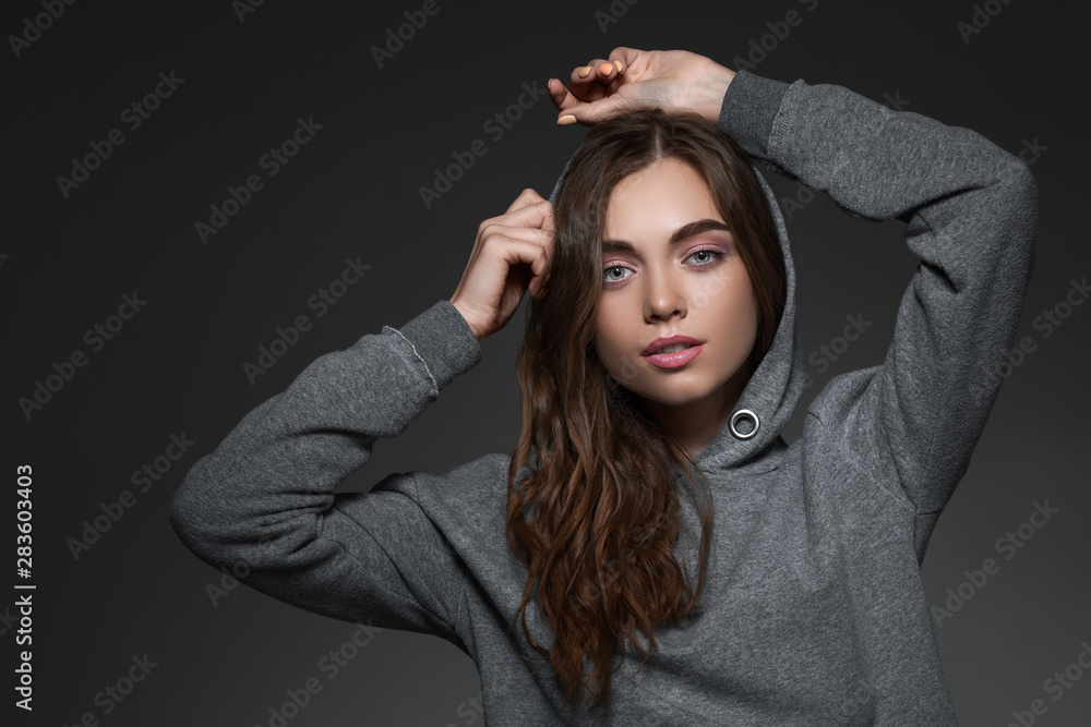 portrait of beautiful woman with long hair in hood on gray background. girl looking at camera. portrait of beautiful woman with long hair in hood on gray background. girl looking at camera.