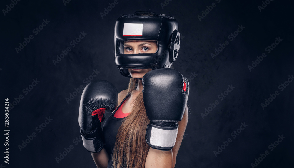 Brave woman is ready to fight, she is wearing boxer gloves and protective helmet.