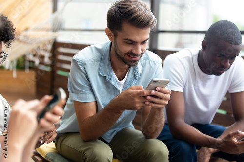 Diverse young people using smartphones hanging out together