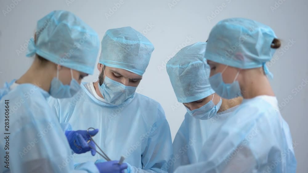 Professional surgeon team working in operation room, nurse smiling at camera Professional surgeon team working in operation room, nurse smiling at camera