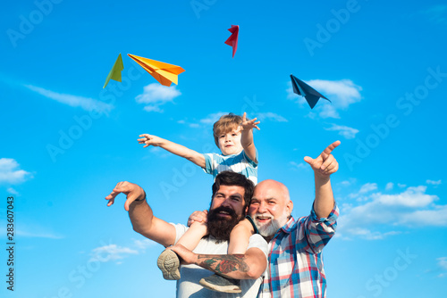 Young boy with father and grandfather enjoying together on blue sky background. Enjoy family together. Father and son with grandfather - happy loving family.