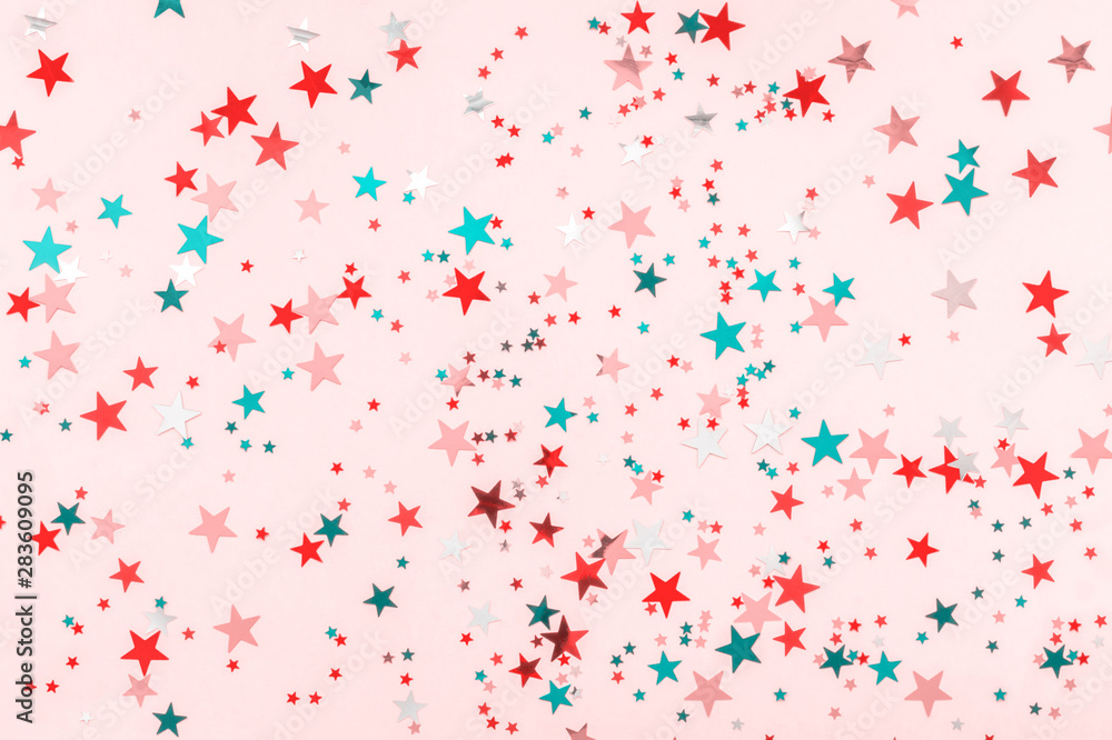 Multi-colored stars glitter on pink background. Festive holiday pastel backdrop. Celebration concept. Decorative Christmas and New Year party background. Top view, flat lay. Horizontal Multi-colored stars glitter on pink background. Festive holiday pastel backdrop. Celebration concept. Decorative Christmas and New Year party background. Top view, flat lay. Horizontal