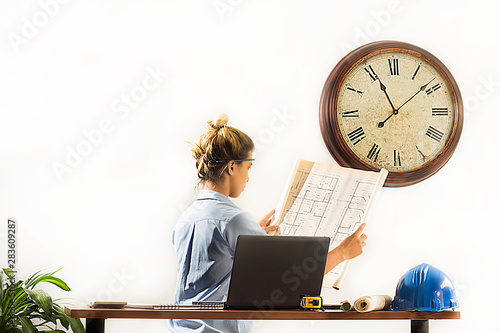 Female architect looking at blueprints of construction drawings in her office