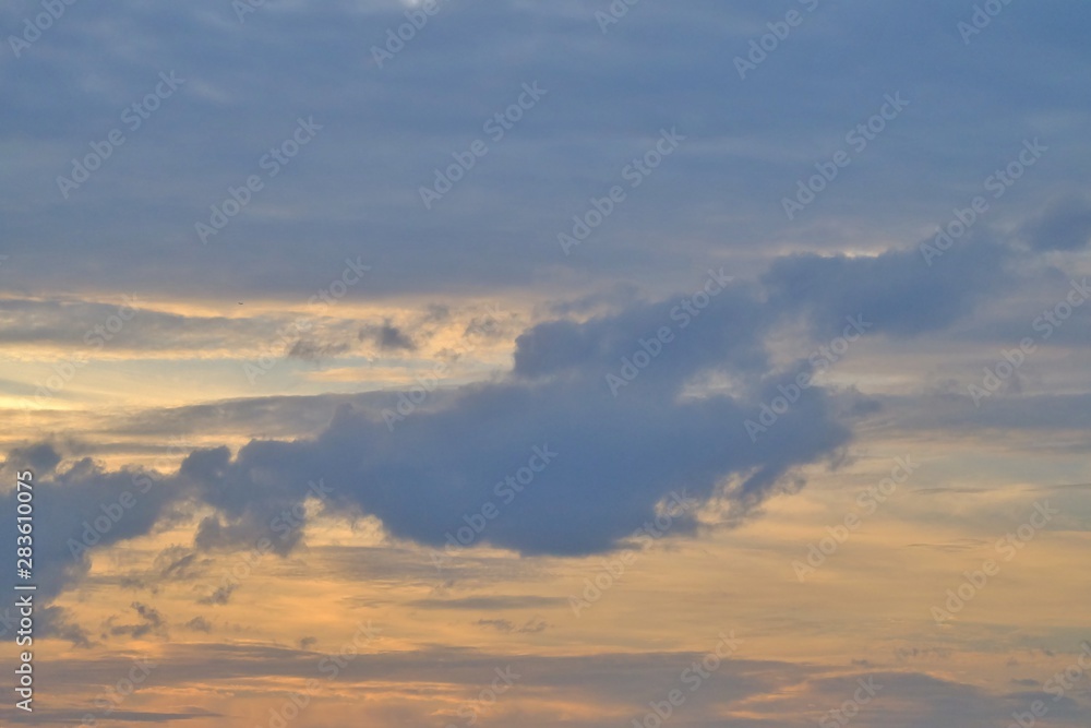 Blue fluffy clouds with colorful sky and sun beams at dusk for background texture 