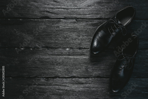 Man black shoes on a black wooden floor. Business flat lay background with a copy space.