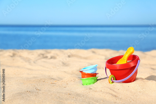 Set of plastic beach toys on sand near sea. Space for text