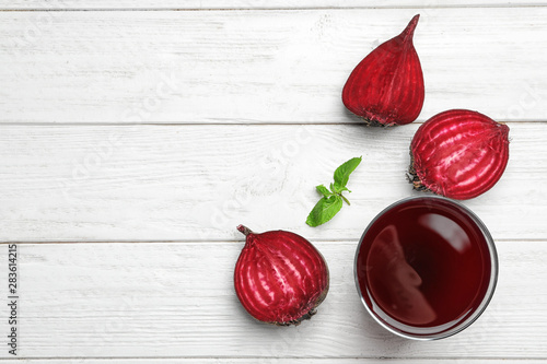 Flat lay composition with fresh beet juice on white wooden background. Space for text photo