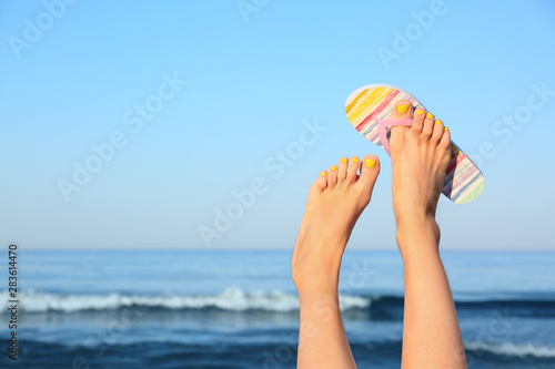 Closeup of woman wearing flip flop near sea, space for text. Beach accessories