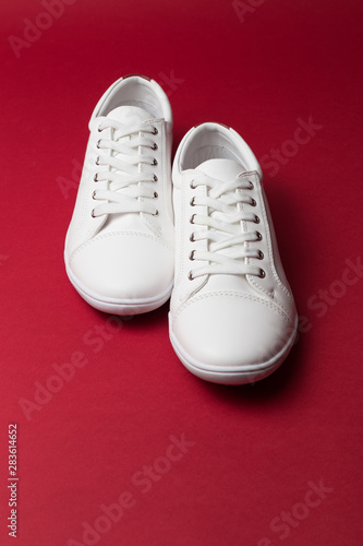 Pair of white trendy sneakers on red background. Place for text.