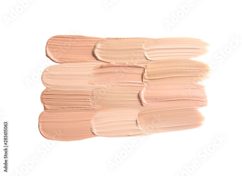 Samples of different foundation shades on white background, top view
