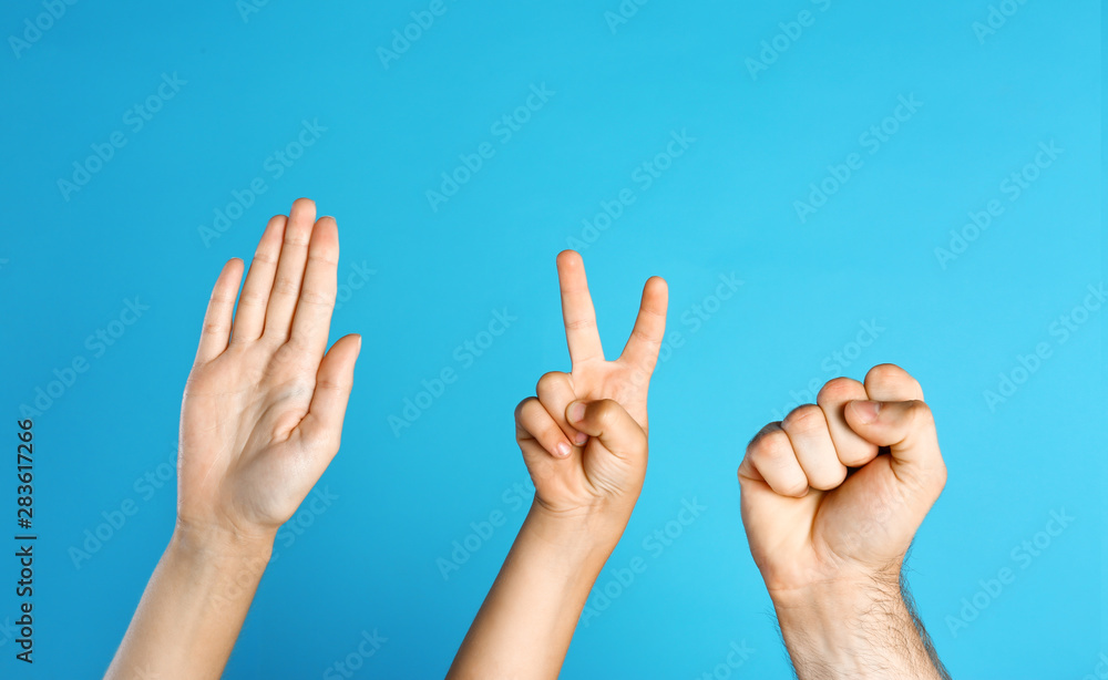 Family playing rock, paper and scissors on blue background, closeup Family playing rock, paper and scissors on blue background, closeup
