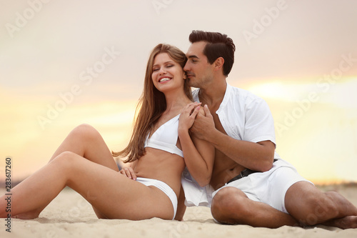 Happy young couple relaxing together on sea beach at sunset © New Africa