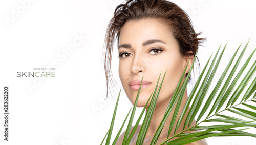Beautiful young woman with green tropical leaf. Spa, skincare and wellness concept