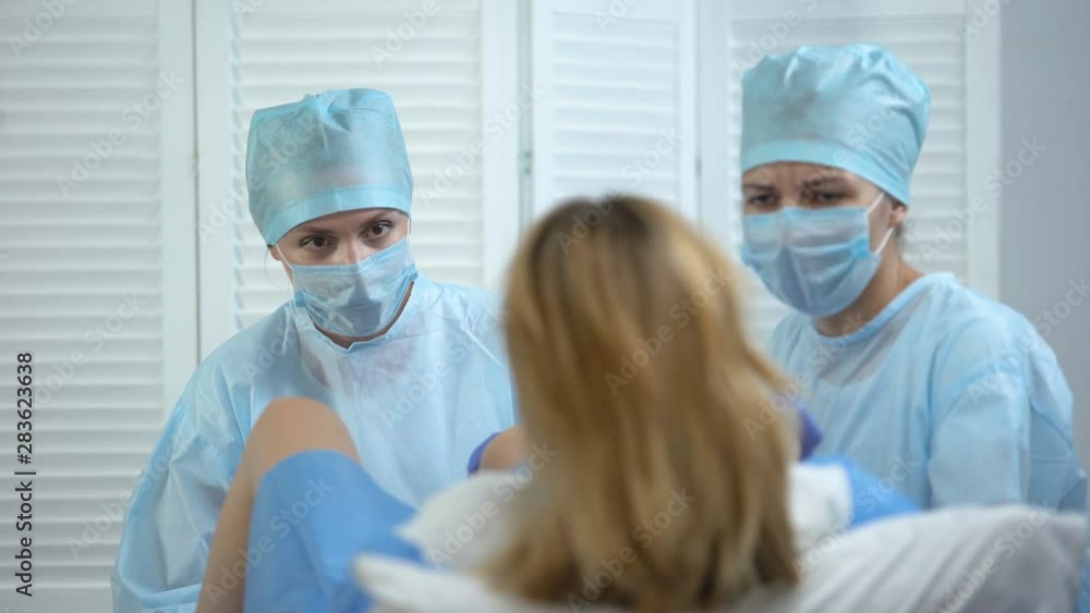Obstetricians assisting woman pushing to give child birth, maternity ward Obstetricians assisting woman pushing to give child birth, maternity ward