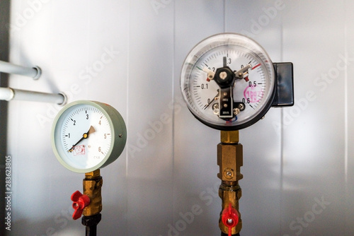 The equipment of the boiler-house, - valves, tubes, pressure gauges, thermometer. Close up of manometer, pipe, flow meter, water pumps and valves of heating system in a boiler room