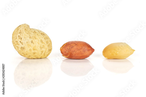 Group of three whole natural yellow peanut in closeup isolated on white background