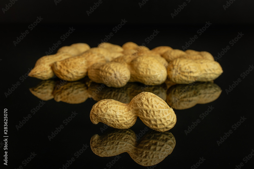 Lot of whole natural yellow peanut one is in the front isolated on black glass Lot of whole natural yellow peanut one is in the front isolated on black glass