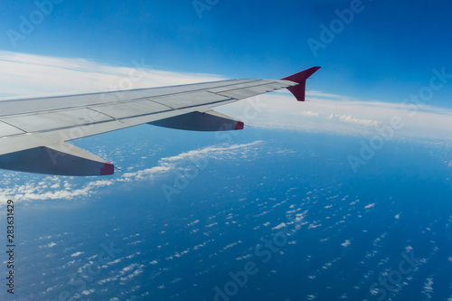 Airplane wing with blue sky and ocean background