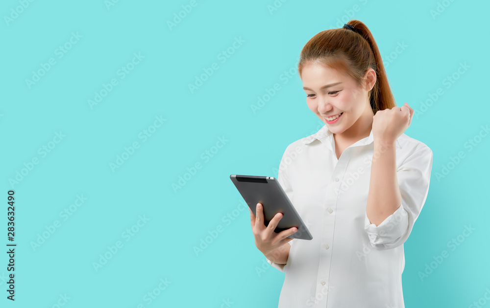 Young smiling Asian woman holding digital tablet with amazed for success on light blue background. Young smiling Asian woman holding digital tablet with amazed for success on light blue background.
