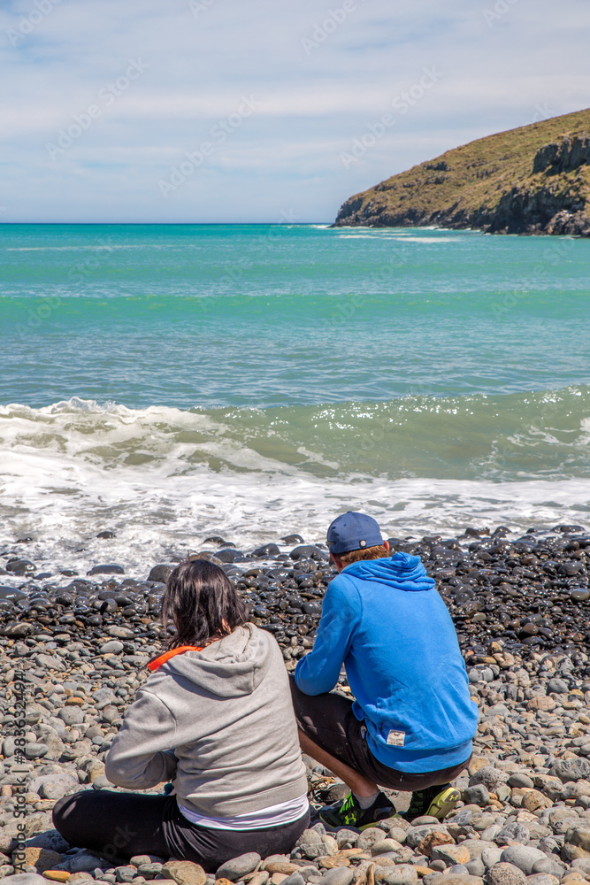 A couple enjoy the picturesque landscape at a bay in the Banks Peninsula area, summertime, Canterbury, New Zealand