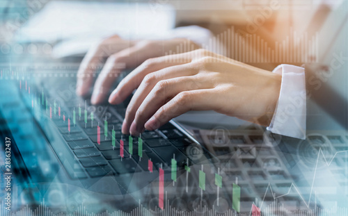 Double exposure of hand businessman using computer laptop and financial graph on building background, stock market financial concept.