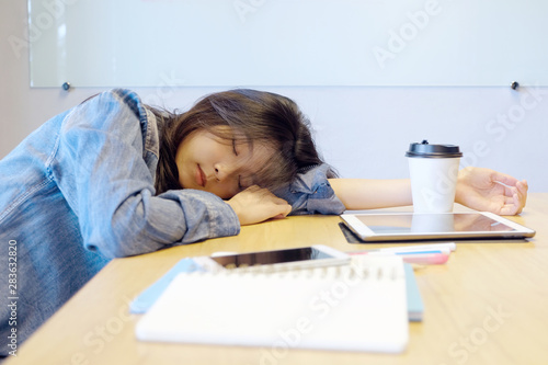 Tired asian woman sleeping at office desk. Young asian woman university student fell asleep in classroom, Creative casual woman sleeping at her working place