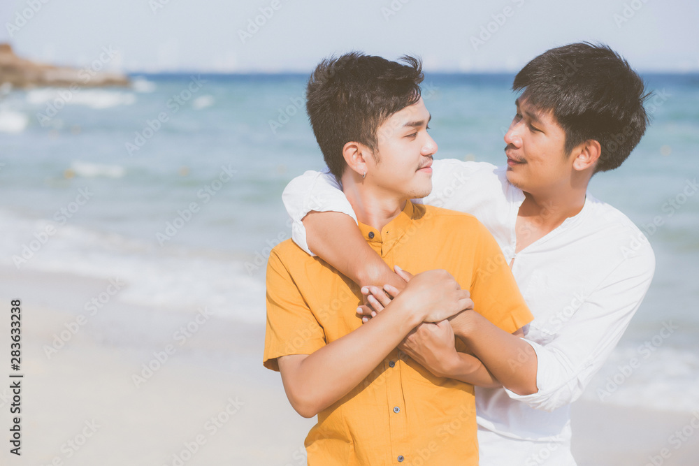 Homosexual portrait young asian couple standing hug together on beach in summer, asia gay going tourism for leisure and relax with romantic and happiness in vacation at sea, LGBT concept. Homosexual portrait young asian couple standing hug together on beach in summer, asia gay going tourism for leisure and relax with romantic and happiness in vacation at sea, LGBT concept.