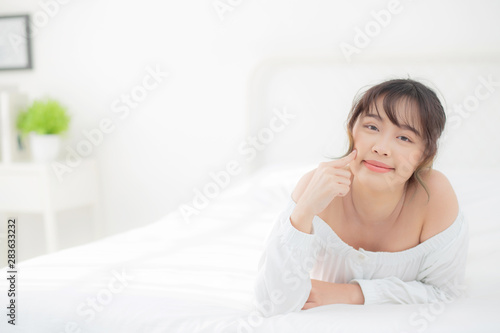Portrait beautiful young asian woman smile while wake up healthy and wellness at morning in the bedroom, beauty asia girl lying skin care and makeup cosmetic with happy, lifestyle and relax concept.