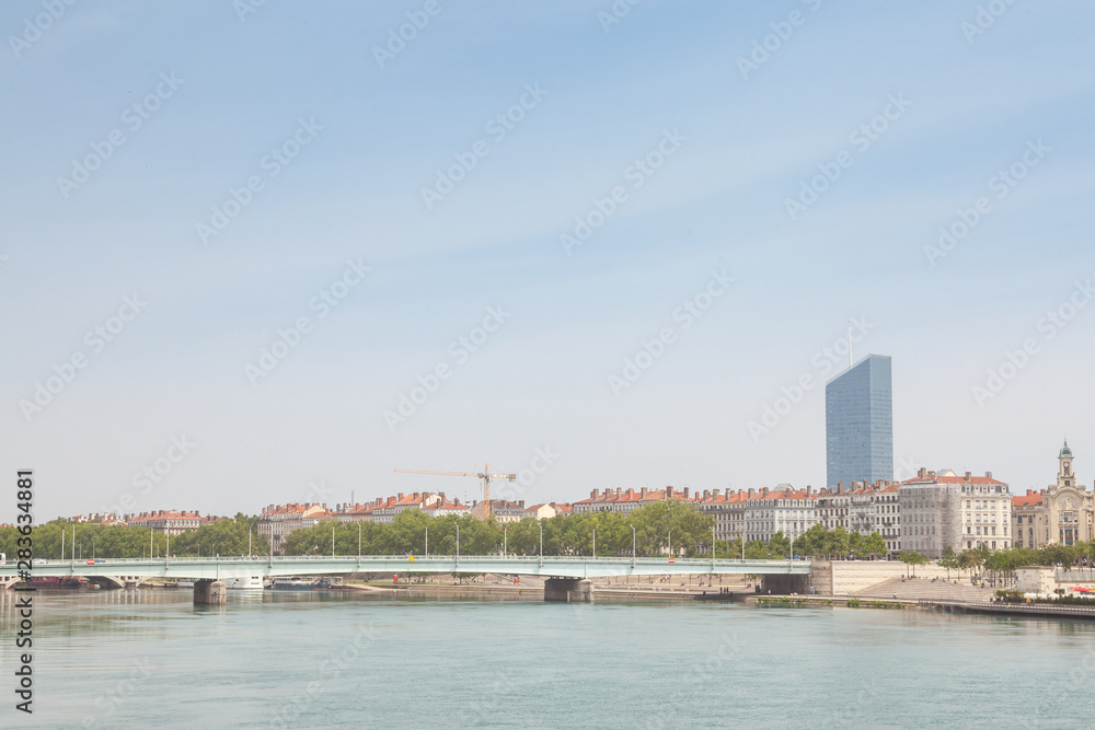 Pont de la Guillotiere bridge in Lyon, France over a panorama of the riverbank of the Rhone river (Quais de Rhone) with older buildings and a modern skyline in background