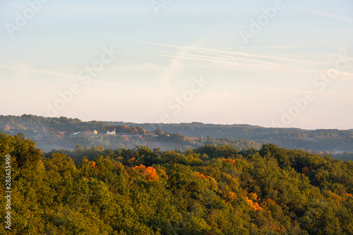 Morning mist rises over a dense forest in the Perigord region of France