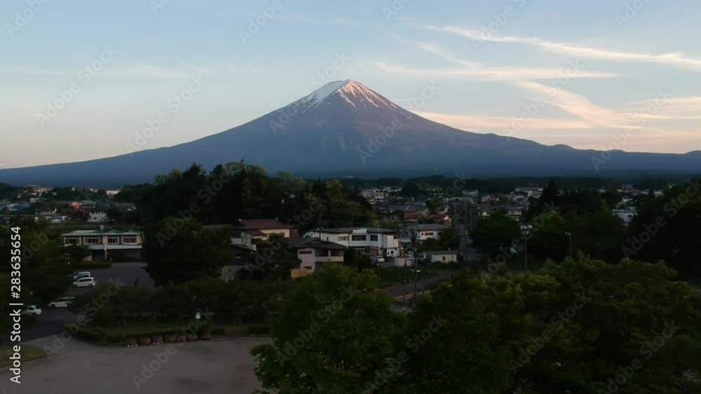Mountain Fuji scene from a garden at the town of Fujikawaguchiko. With a crane up from tree and aerial view of clear Mount Fuji with foreground of a town. Mountain Fuji scene from a garden at the town of Fujikawaguchiko. With a crane up from tree and aerial view of clear Mount Fuji with foreground of a town.