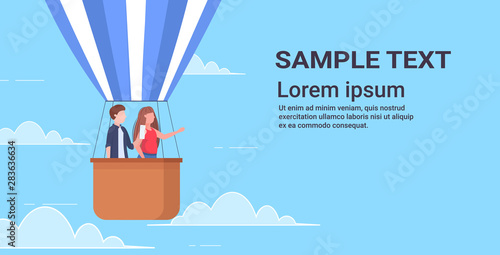 couple flying in basket of hot air balloon man taking photo on smartphone camera woman pointing hand at something travel concept copy space flat horizontal