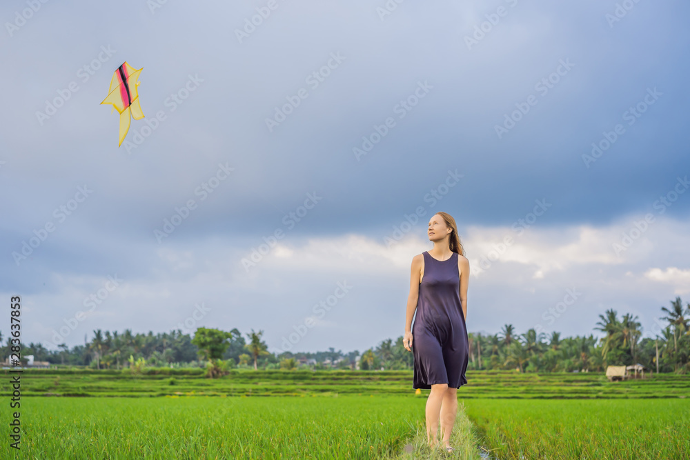 Young woman tourist launches a kite in a rice field in Ubud, Bali Island, Indonesia Young woman tourist launches a kite in a rice field in Ubud, Bali Island, Indonesia
