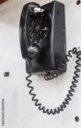 Vintage black rotary dial telephone hanging on the wall photo