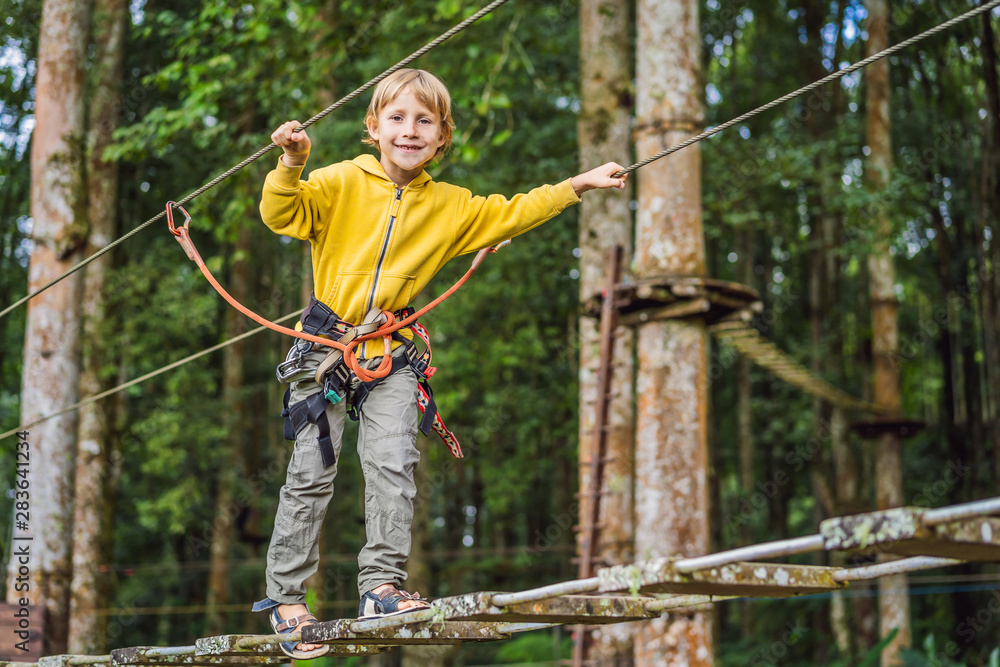 Little boy in a rope park. Active physical recreation of the child in the fresh air in the park. Training for children Little boy in a rope park. Active physical recreation of the child in the fresh air in the park. Training for children