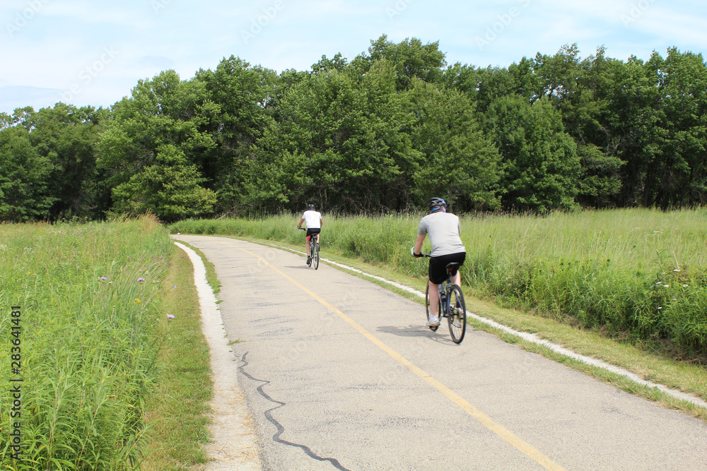 Fototapeta premium Two men cycling in summer at Morton Grove, Illinois' Miami Woods