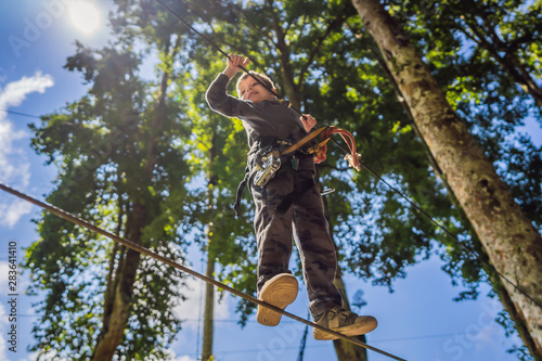 Little boy in a rope park. Active physical recreation of the child in the fresh air in the park. Training for children