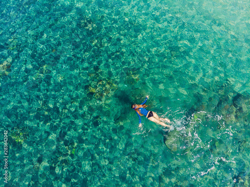 Happy woman in snorkeling mask dive underwater with tropical fishes in coral reef sea pool. Travel lifestyle, water sport outdoor adventure, swimming lessons on summer beach holiday. Aerial view from
