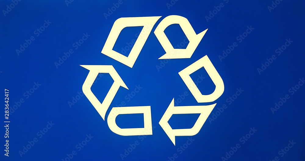 Blue recycle logo on an aluminum receptacle, promoting the use of recycled materials to help save the environment. Blue recycle logo on an aluminum receptacle, promoting the use of recycled materials to help save the environment.