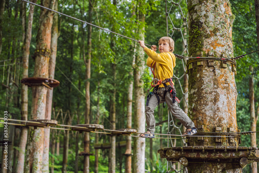 Little boy in a rope park. Active physical recreation of the child in the fresh air in the park. Training for children Little boy in a rope park. Active physical recreation of the child in the fresh air in the park. Training for children