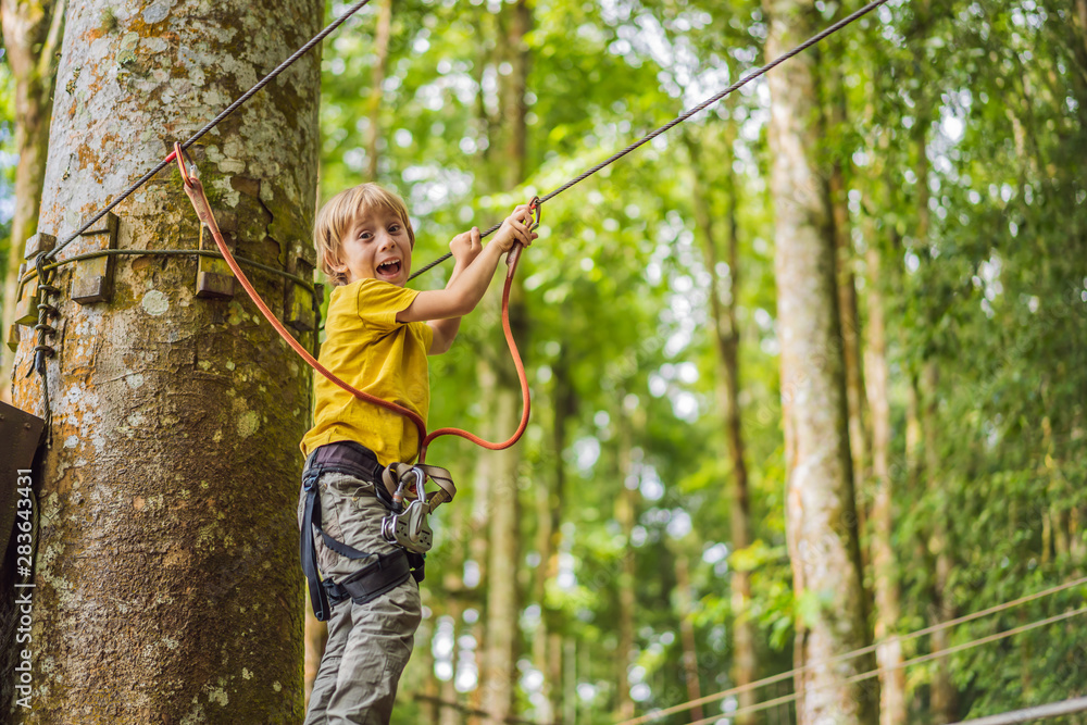 Little boy in a rope park. Active physical recreation of the child in the fresh air in the park. Training for children Little boy in a rope park. Active physical recreation of the child in the fresh air in the park. Training for children