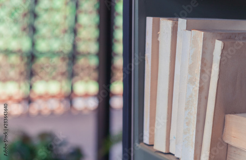 Old textbook and books on shelf in library with beatiful blurred bokeh background