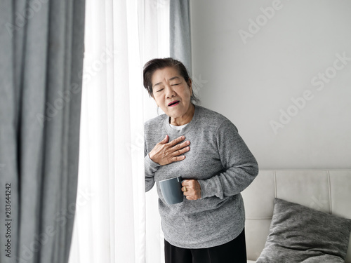Asian senior woman having heart attack while staying at home alone, lifestyle concept.