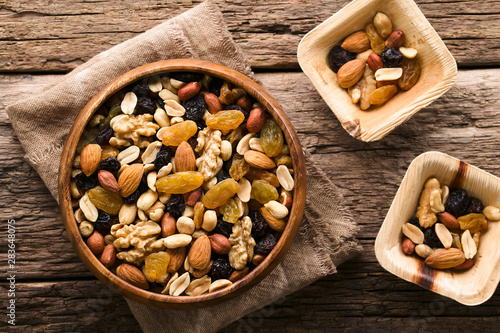 Healthy trail mix snack made of nuts (walnut, almond, peanut) and dried fruits (raisin, sultana) in wooden bowl, photographed overhead (Selective Focus, Focus on the trail mix in the big bowl) photo