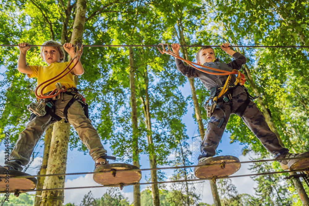 Two little boys in a rope park. Active physical recreation of the child in the fresh air in the park. Training for children